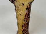 a brown and black vase sitting on a white surface