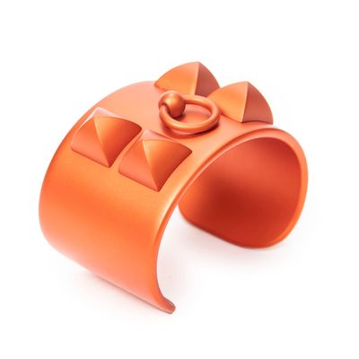 an orange cuff bracelet with a bow on it on a white surface