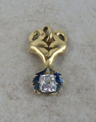 a gold pendant with a diamond on it on a marble surface
