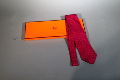 purple tie with orange box on grey surface with white background