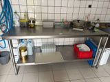 une cuisine équipée d'une table en inox et d'un évier