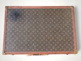 an old louis vuitton suitcase sitting on top of a white surface