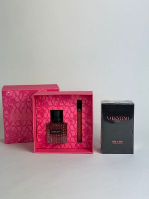 an image of a bottle of perfume in a pink box next to a box of perfume