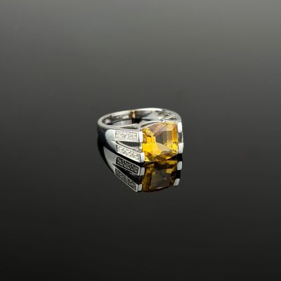 un gros plan d'une bague ornée d'une pierre jaune sur un fond noir