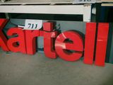 une grande enseigne rouge sur laquelle est inscrit « Kartell »