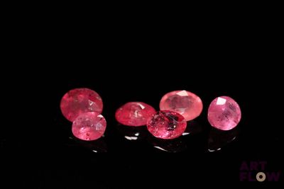 three pink diamonds on a black surface with a black background