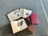 four books on the floor with a pen on top of them
