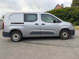 grey van parked in a parking lot with trees and bushes in the background