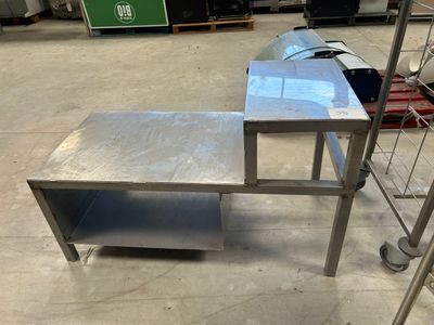 une table en métal surmontée d'une étagère, dans un entrepôt