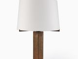 La lampe est en bois et est munie d'un abat-jour blanc.