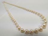 a close up of a necklace with pearls on a white surface