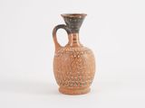 a small brown vase with a black handle on a white surface