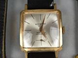 a gold watch sitting on a black leather strap