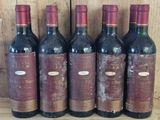 six bouteilles de vin rouge sont alignées sur une étagère en bois