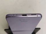 the back of a silver cell phone sitting on top of a wooden stand