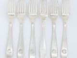 un ensemble composé de six fourchettes et d'un couteau, posé sur un support blanc