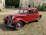 an old red car parked in front of a church