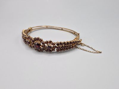 un gros plan d'un bracelet avec une chaîne posé sur une surface blanche