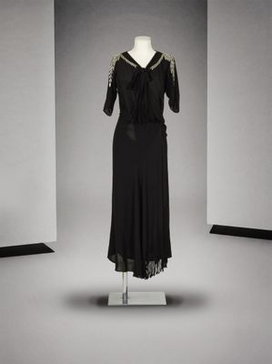 une robe noire posée sur un mannequin devant un mur blanc