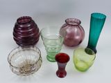 many different colored glass vases and glasses on the table