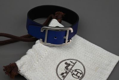 une ceinture en cuir bleu avec une boucle argentée et une pochette en tissu blanc