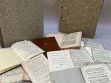 plusieurs livres ouverts posés sur une table à côté d'une pile de documents