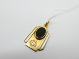 un pendentif en or orné d'une pierre noire au centre