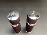 two silver metal pepper shakers sitting on a table