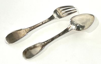 two silver spoons and a fork on a white surface