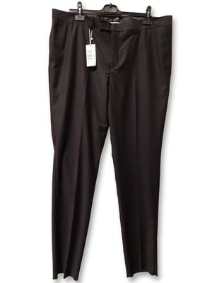 Le pantalon noir est suspendu à un cintre accroché à un mur blanc.