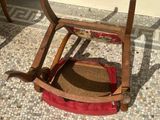 a wooden rocking chair with a red seat on a tiled floor