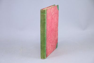 un livre rose et vert posé sur une surface blanche