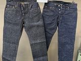 deux paires de jeans suspendues à un portant dans un magasin