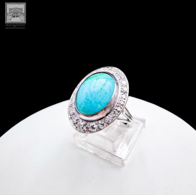 a close up of a ring with a turquoise stone surrounded by diamonds