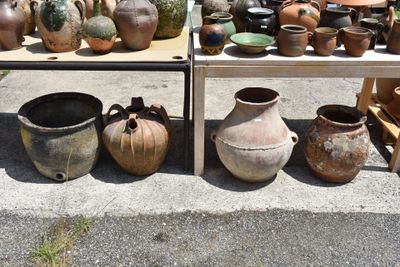 many pots and vases on display on the sidewalk