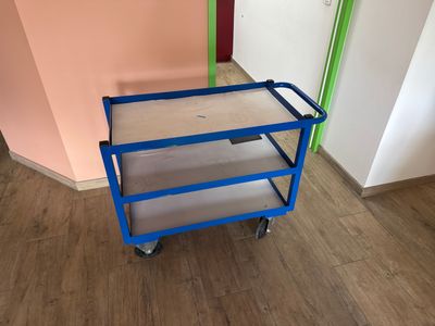 a blue cart sitting on top of a wooden floor next to a pink wall