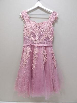 a pink dress hanging on a hanger against a wall