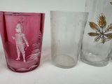 three glasses and a glass vase sitting on a table