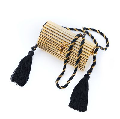 un sac à main noir et doré orné de pompons, sur fond blanc