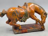 une statue orange et noire représentant un cheval avec un cavalier sur le dos