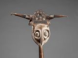 a close up of a wooden mask on a metal stand
