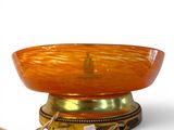 an orange bowl on a gold plate with a rope around it