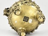 an image of a gold vase on a white surface with a sticker on it