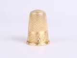 a gold thimble that is sitting on a white surface