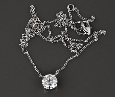 une chaîne en argent ornée d'un pendentif en diamant, posée sur un fond noir