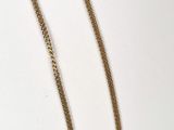 a close up of a gold chain necklace on a white surface