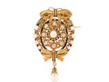 a close up of a brooch with pearls and leaves