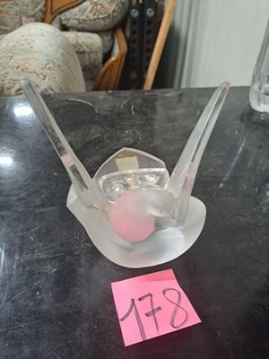 un objet en plastique posé sur une table, sur lequel est collé un autocollant rose