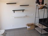 une pièce avec un canapé noir et une étagère sur laquelle sont posés des vêtements