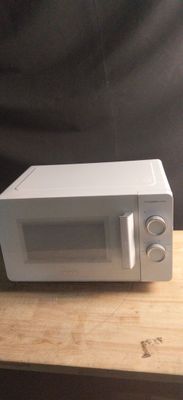 un micro-ondes posé sur une table en bois, sur fond noir